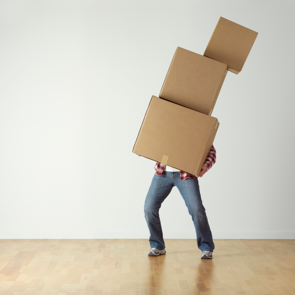man holding several boxes and appearing very unbalanced.
